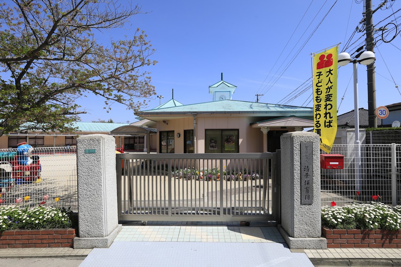 青緑の屋根と花壇のある清華保育園の園舎正面